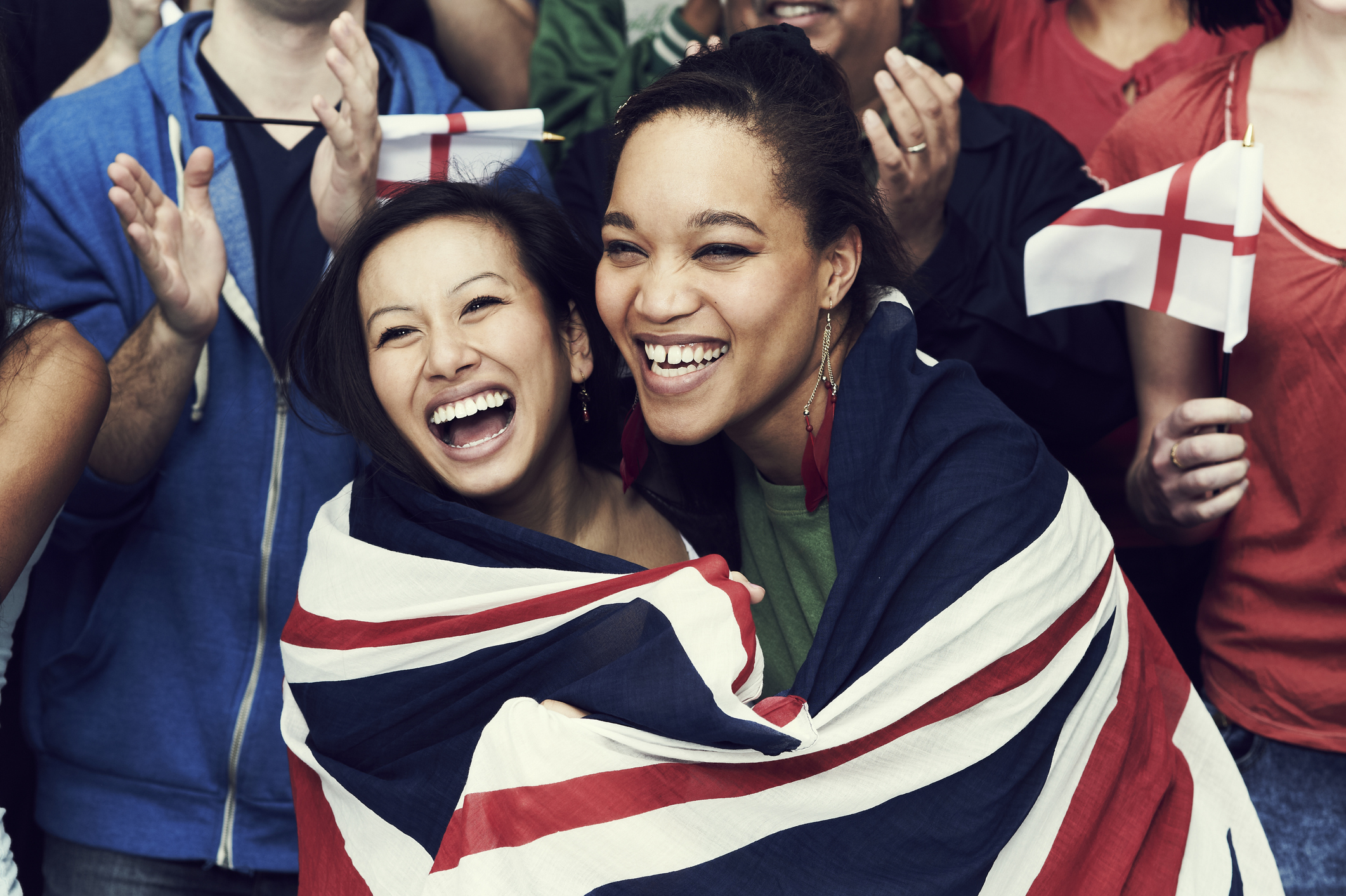 Two women smiling, both wrapped in a United Kingdom flag.
