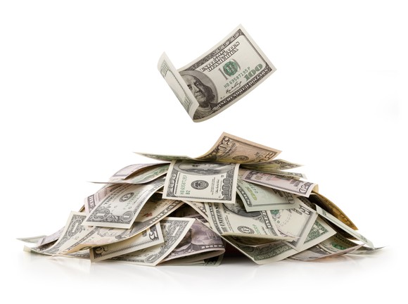 A pile of loose money in all denominations, with a one hundred dollar bill floating above it.