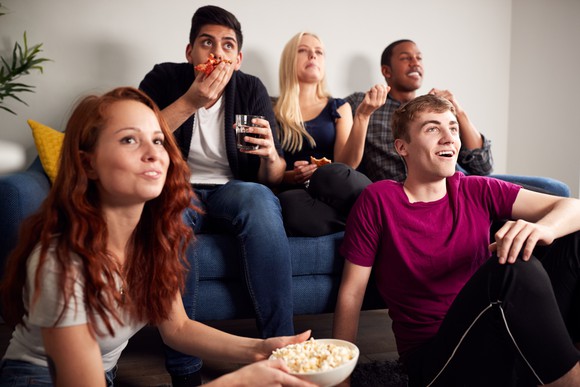 Five young adults watching a program.