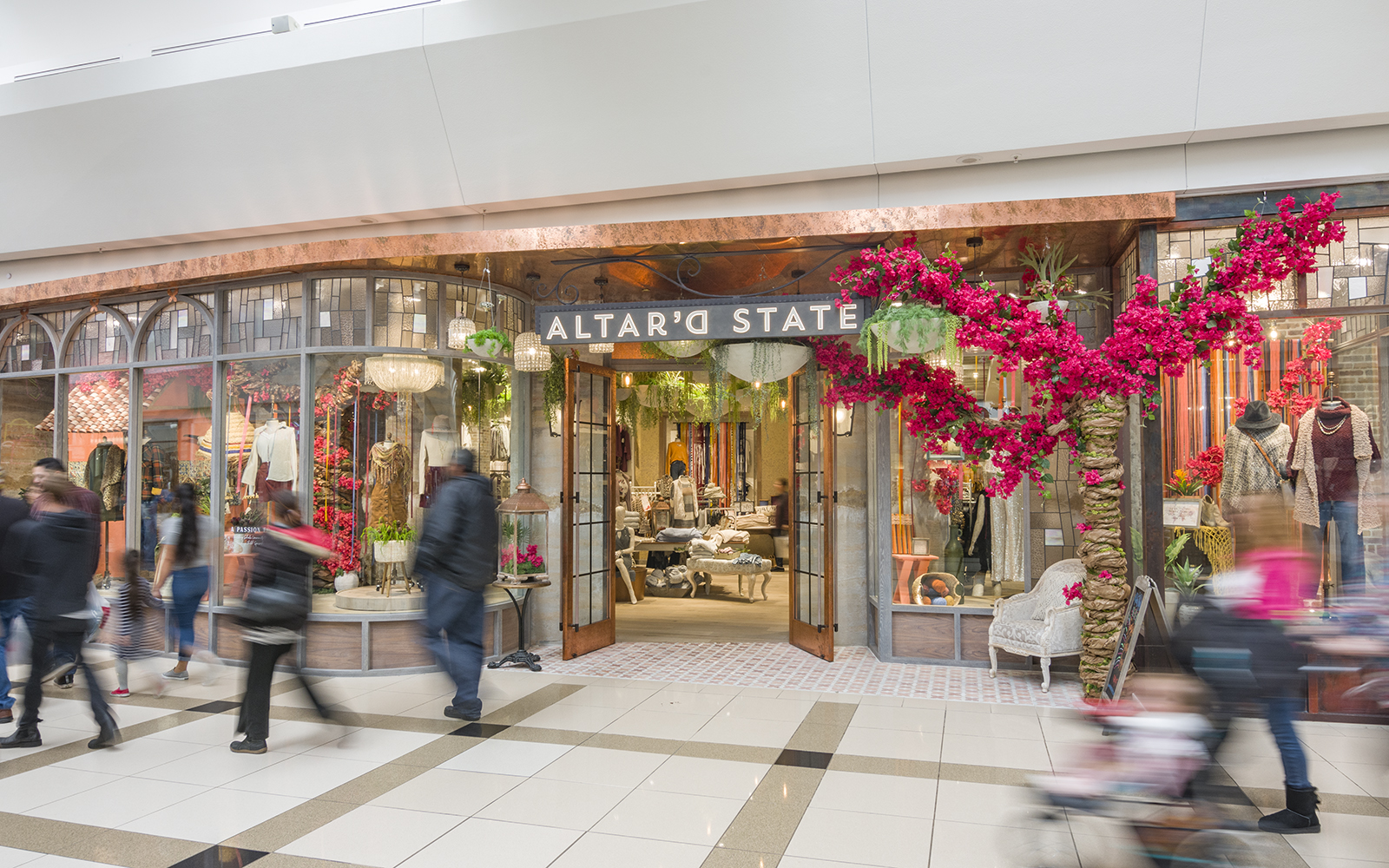 Blurred images of people walking by an Altar'd State store at PREIT's Woodland Mall.