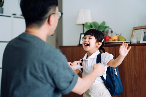 A father getting his daughter ready for school.