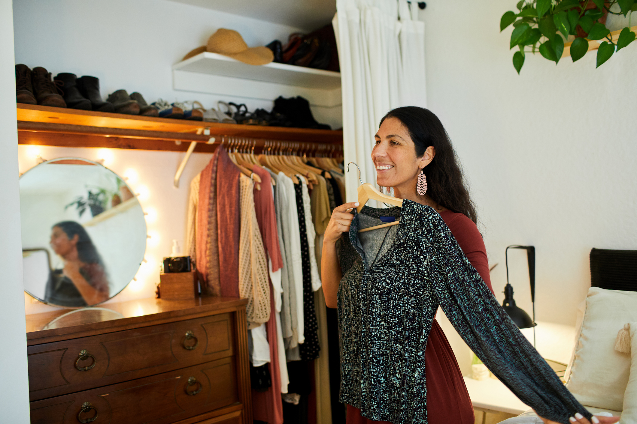 A person holding up a dress against their body and smiling.