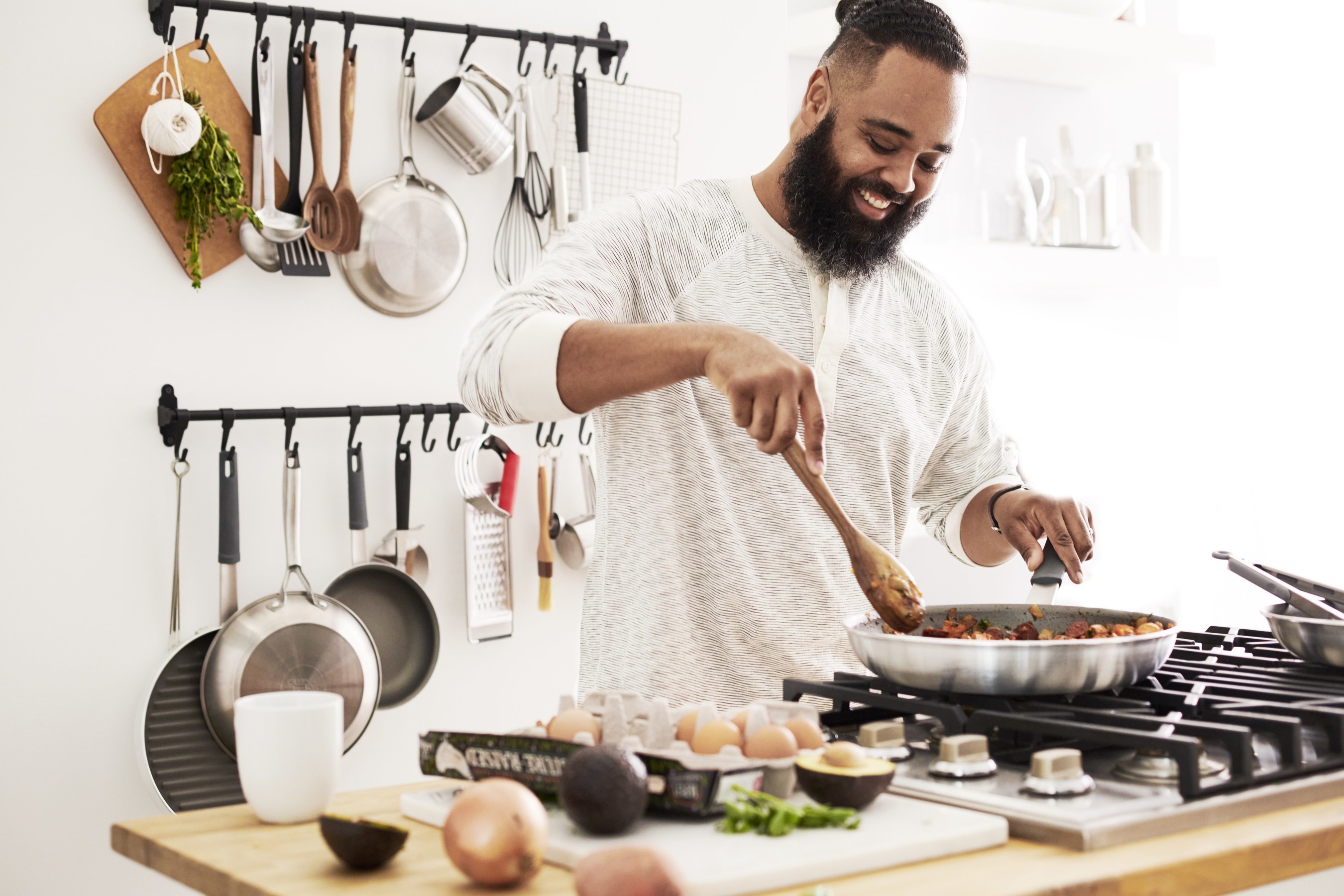 Person in kitchen cooking food in frying pan.