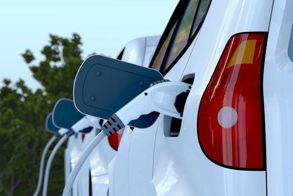 Three electric vehicles sit in a row as their electric plugs are inserted