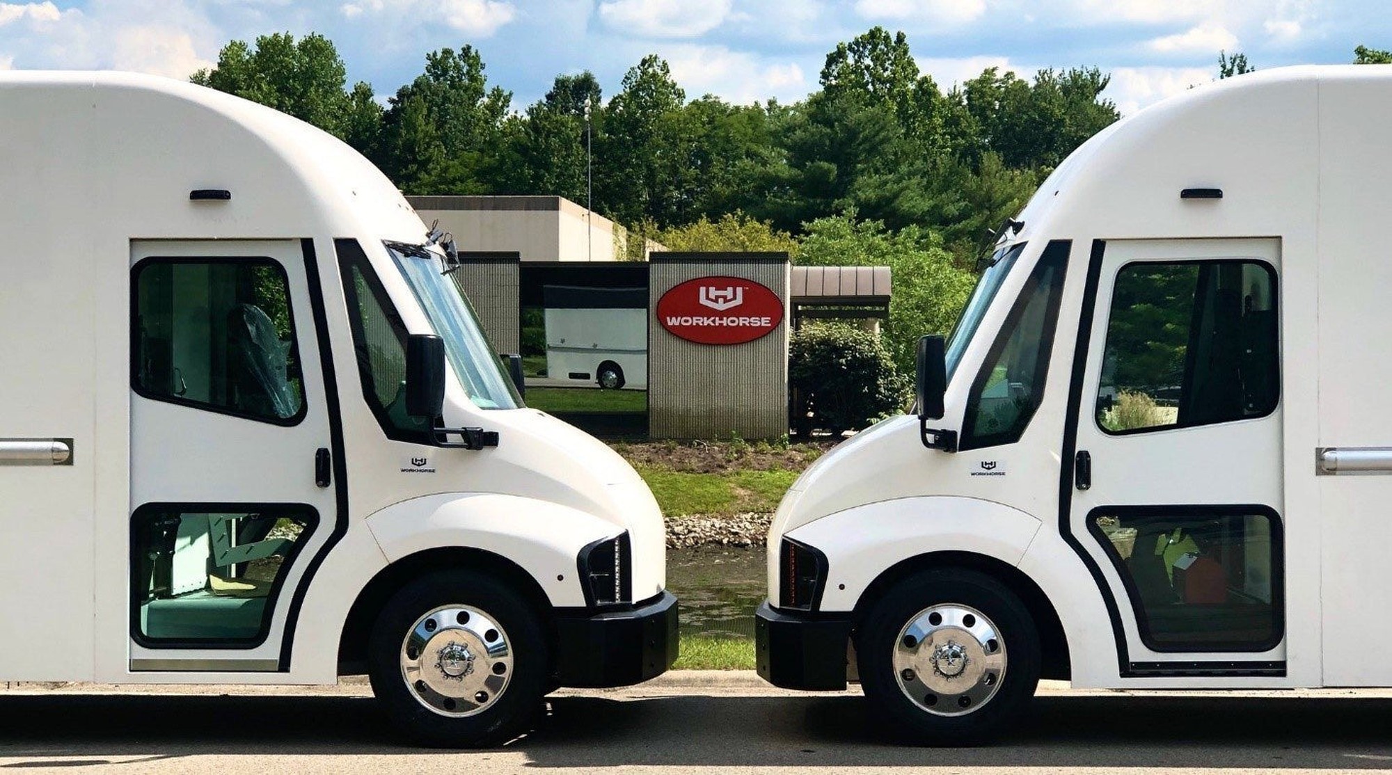 The front of two Workhorse electric vehicles are seen in front of a Workhorse sign