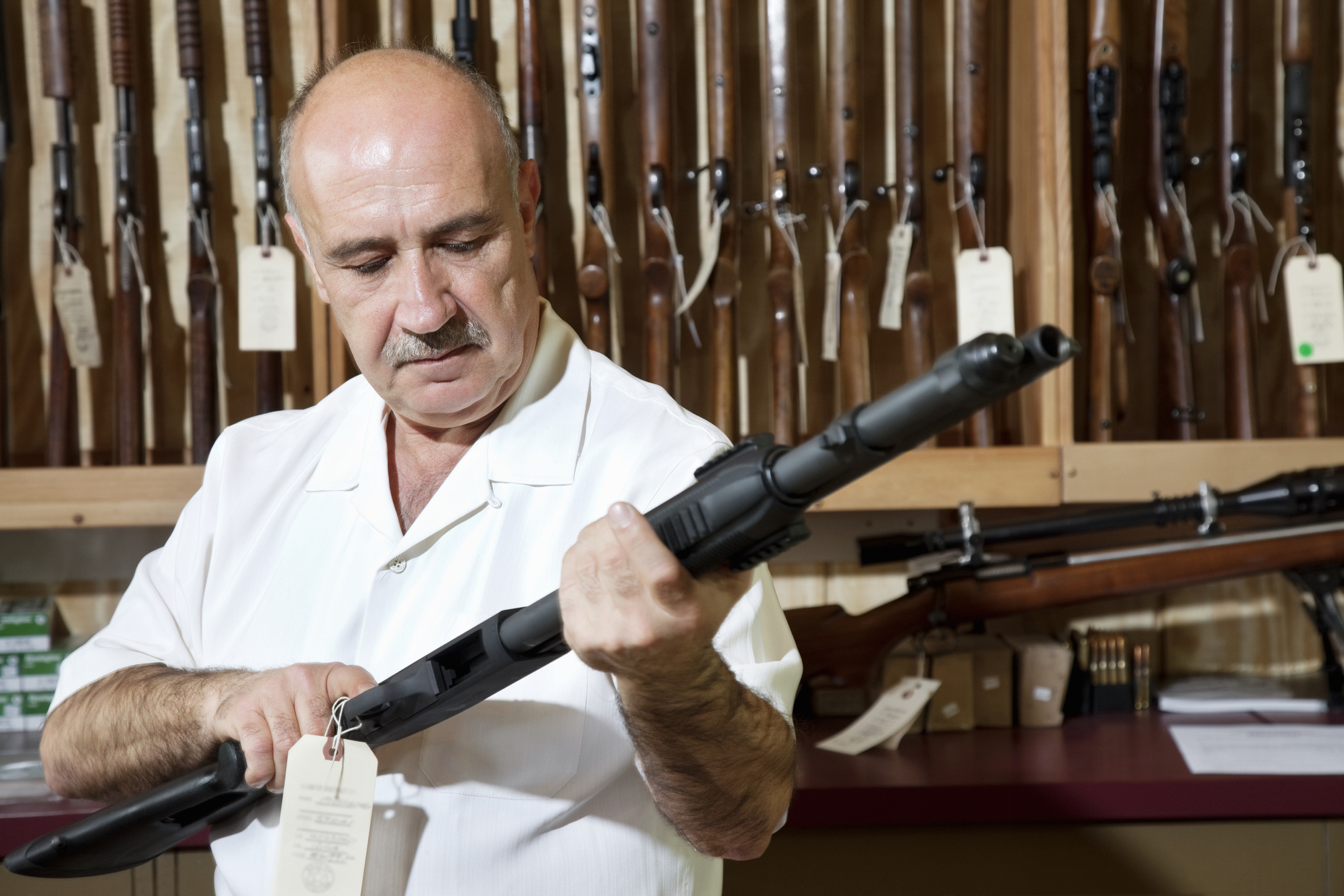 Person holding a shotgun in a gun store.