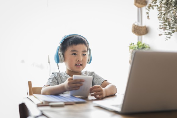 Youth wearing headphones sitting in front of laptop