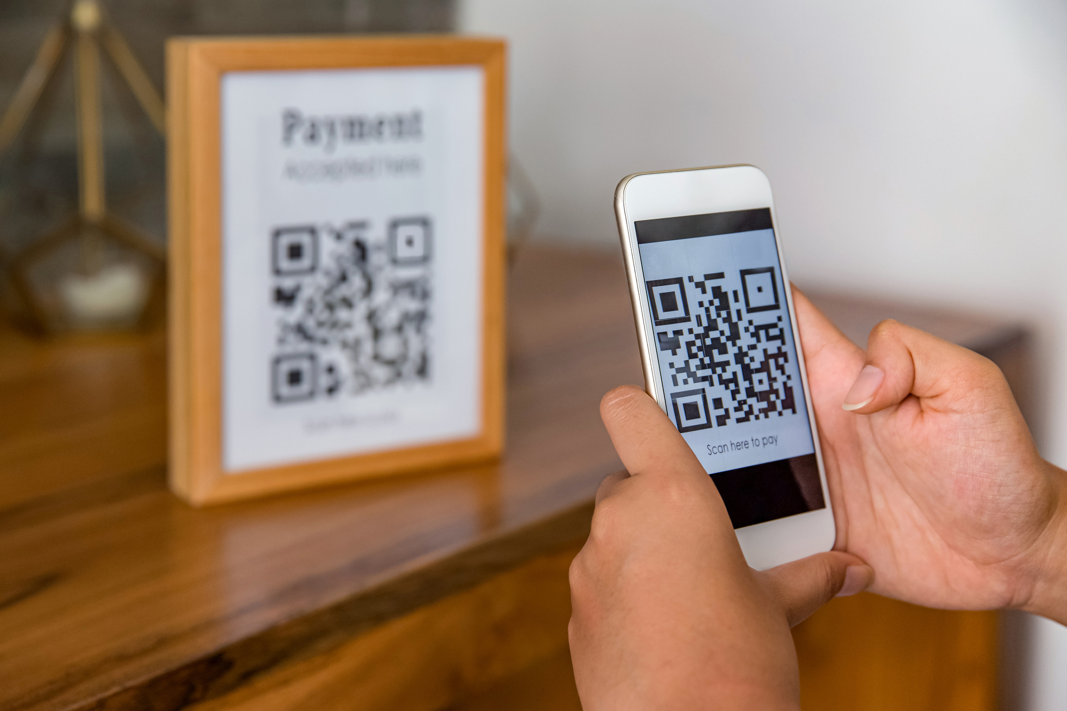 A person makes a payment by scanning a QR code with a phone.