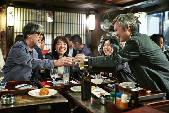 Patrons toasting at a sushi bar. 