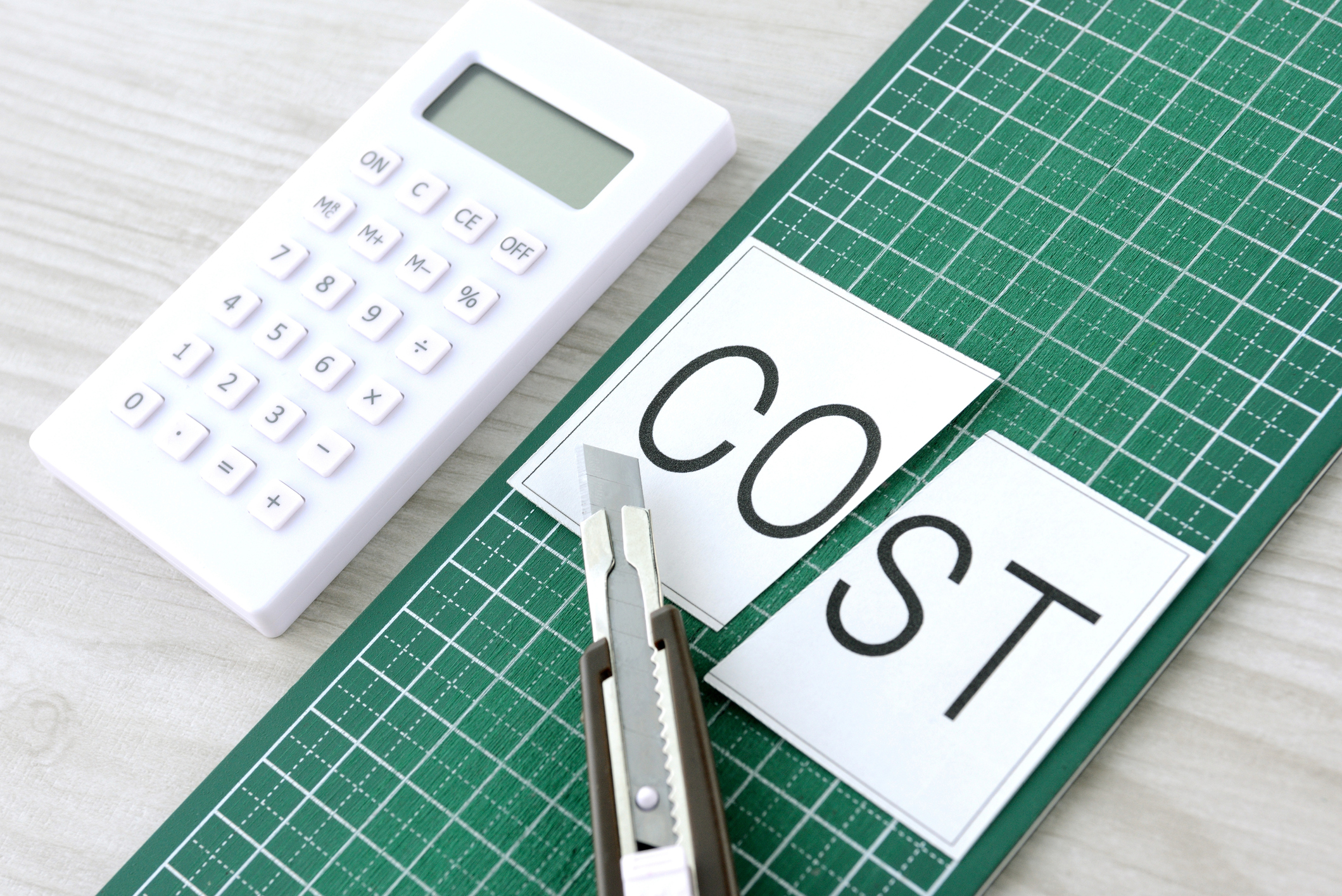 The word cost spelled out on a piece of paper split in half.