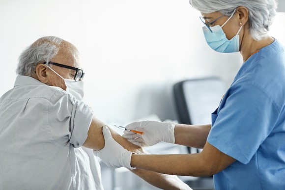 A nurse vaccinates an older person in a clinic.