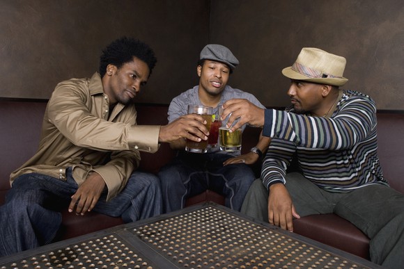 Three people around a table drinking beer.