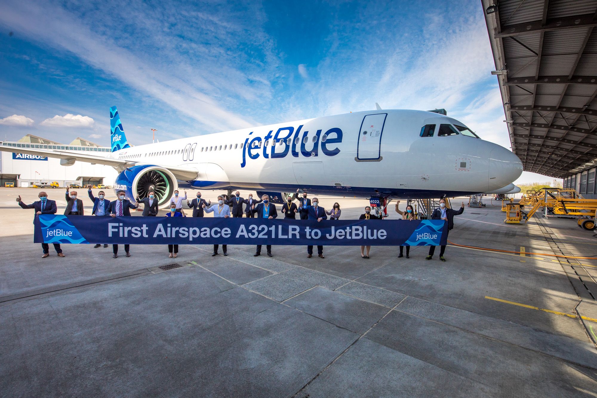 People standing on the tarmac in front of a JetBlue plane celebrating the handover of JetBlue's first A321LR.