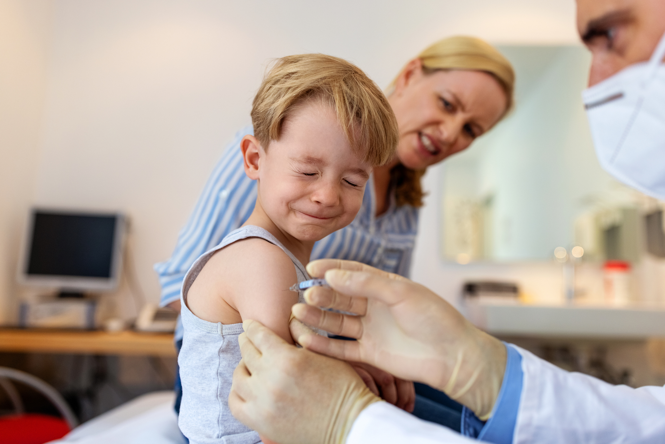 Child wincing as he receives a vaccination shot.