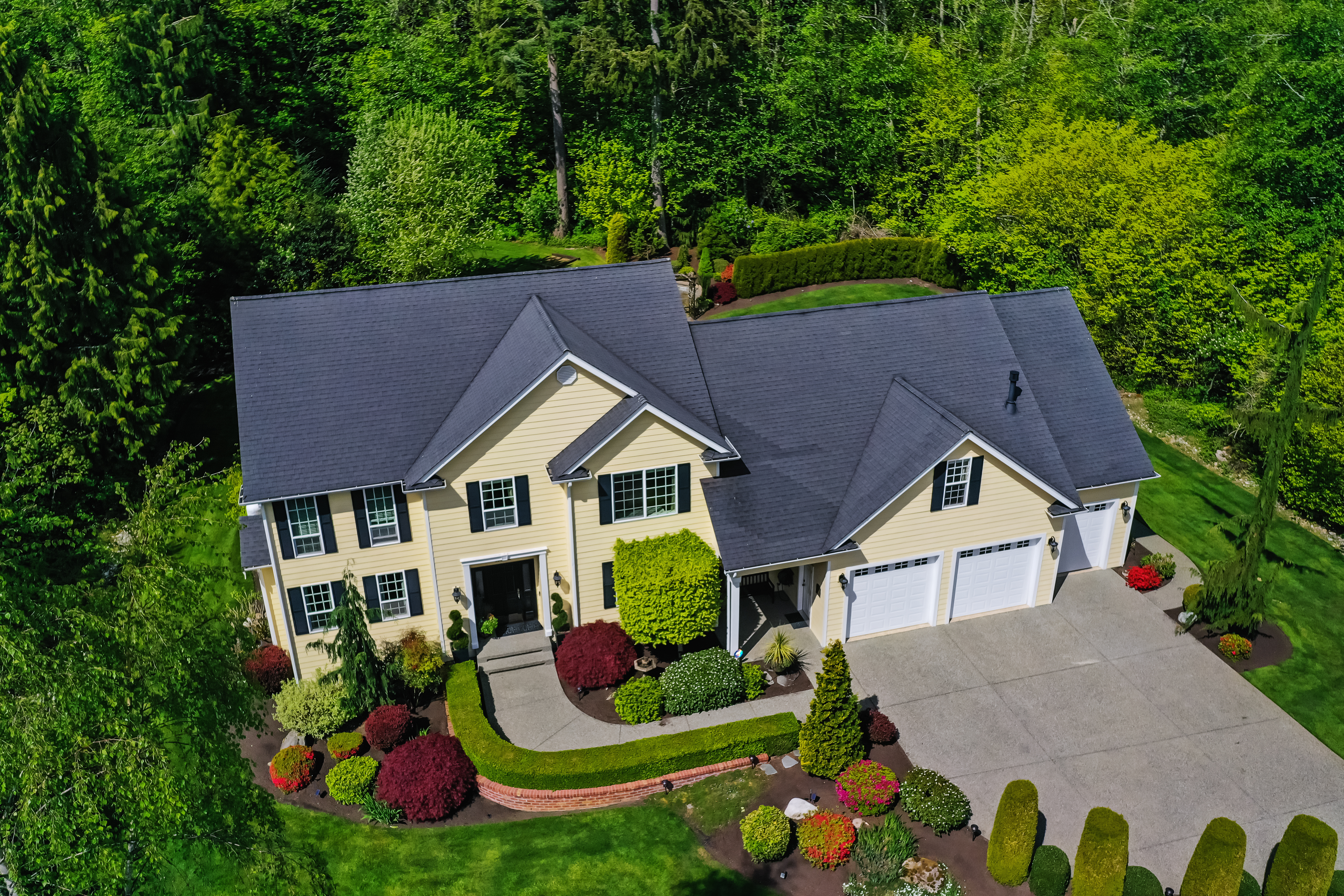Aerial view of a nice double story house surrounded by leafy greenery.