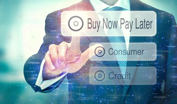 A person in a suit points to a button that says "buy now, pay later." 