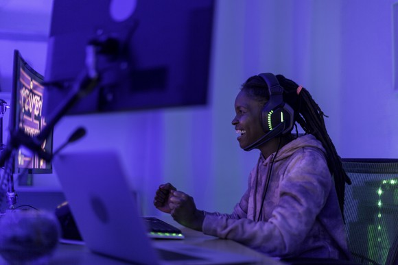 A young person playing PC video games in a dark room.