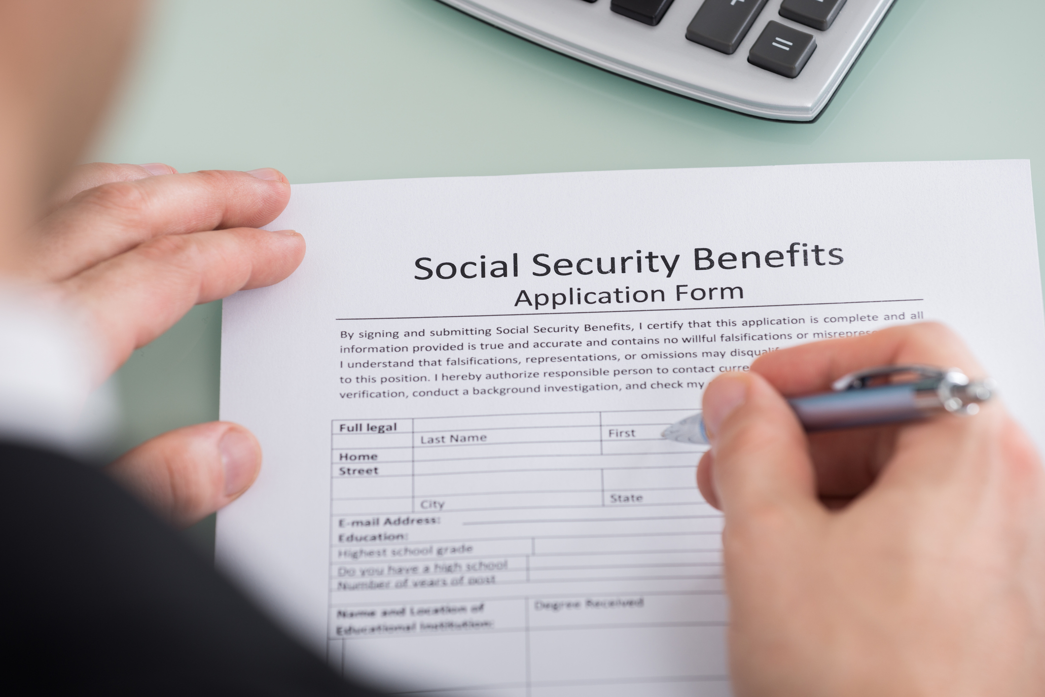 Person filling out Social Security benefits application form.