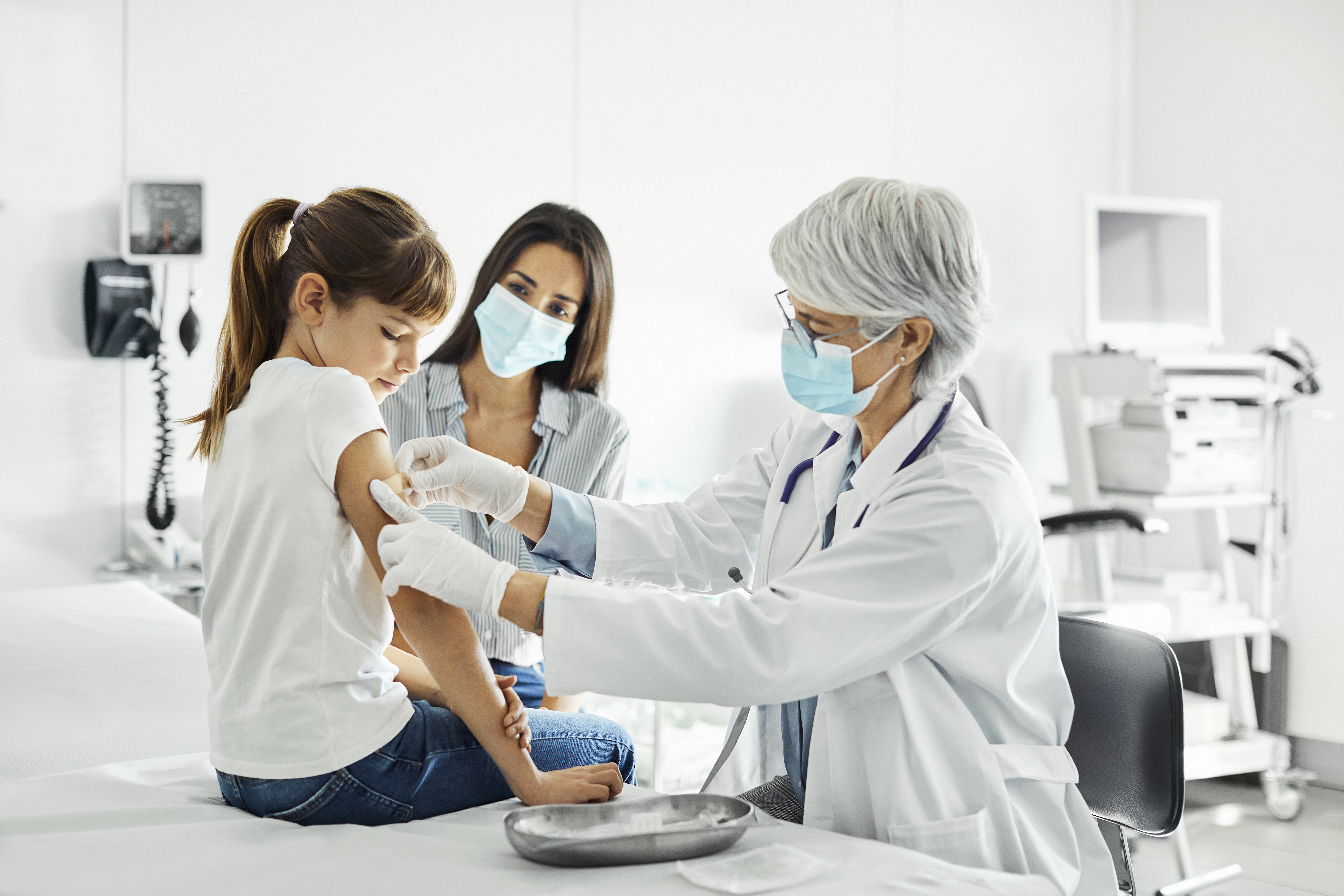 A healthcare worker puts a bandage on a child's arm.