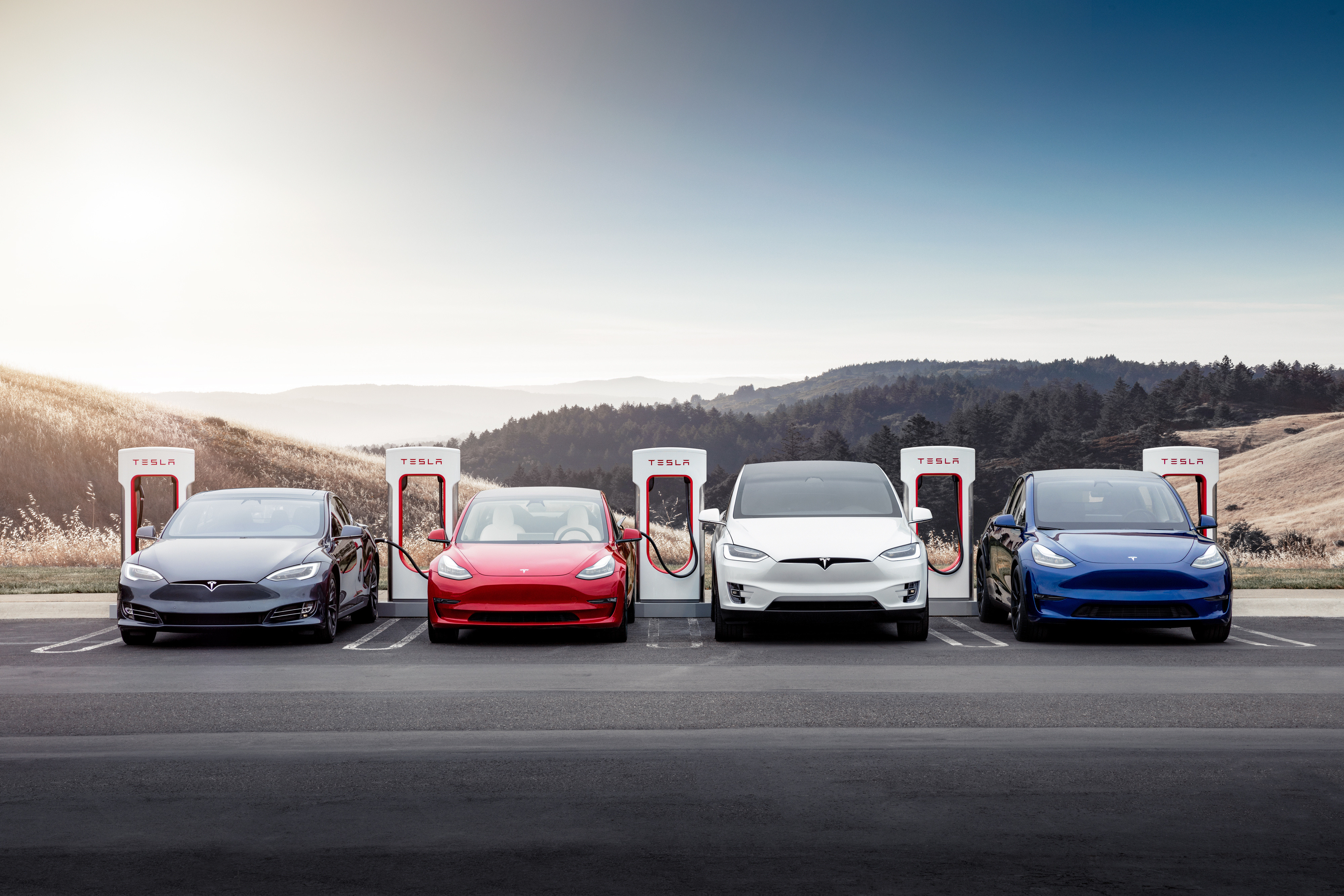 Four Tesla vehicles charging at a Supercharger network location.