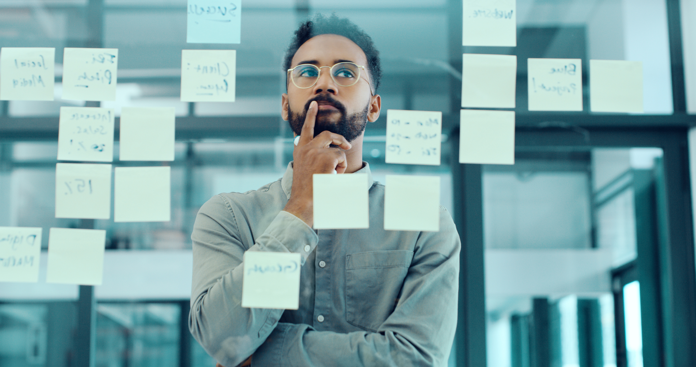 A businessman studies notes attached to a window.