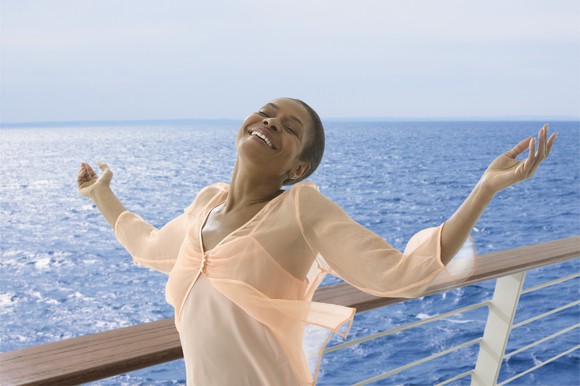 Cruise customer on cruise ship balcony with open arms enjoying the breeze. 