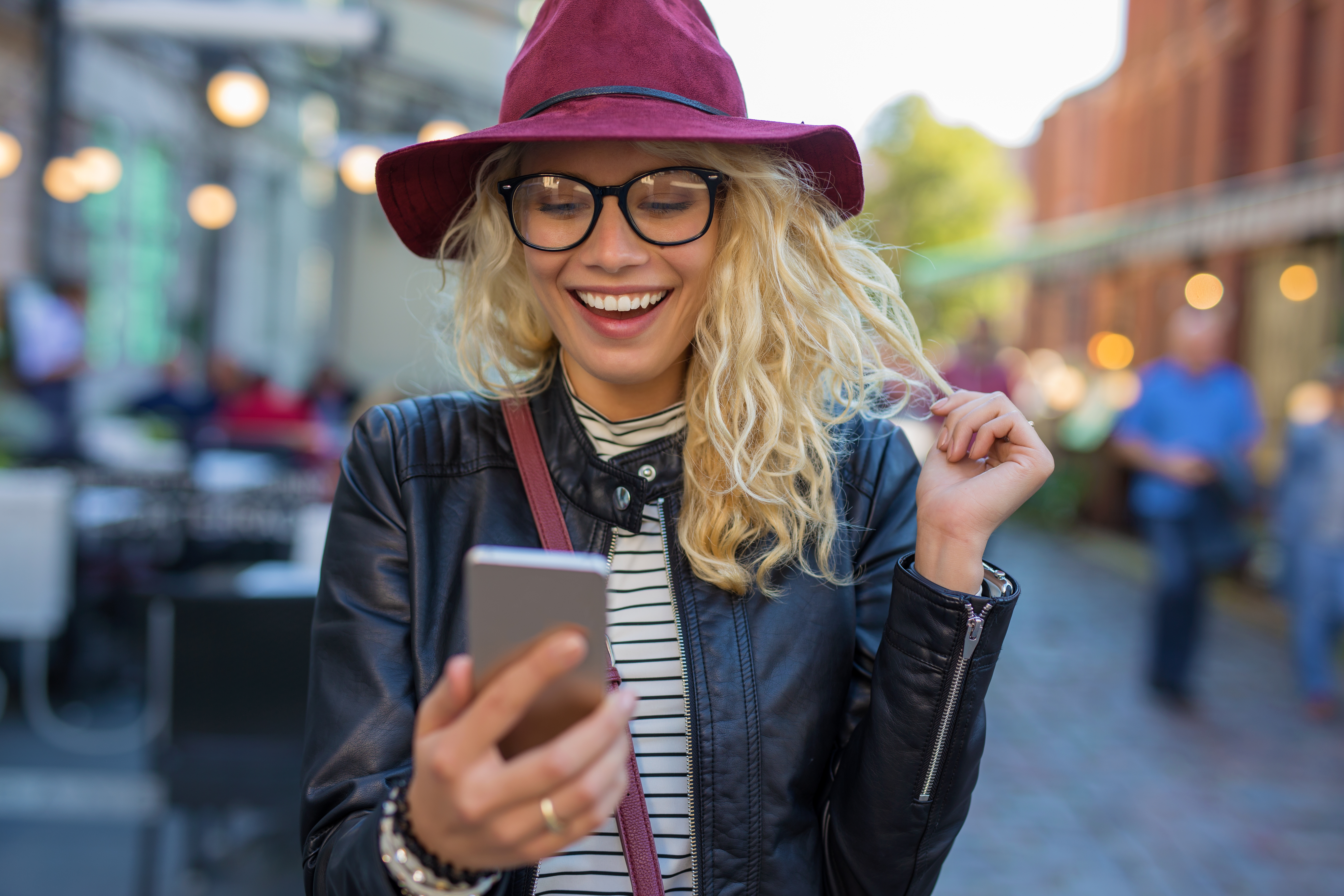 Woman walking down a busy street and browsing the internet on a smartphone.