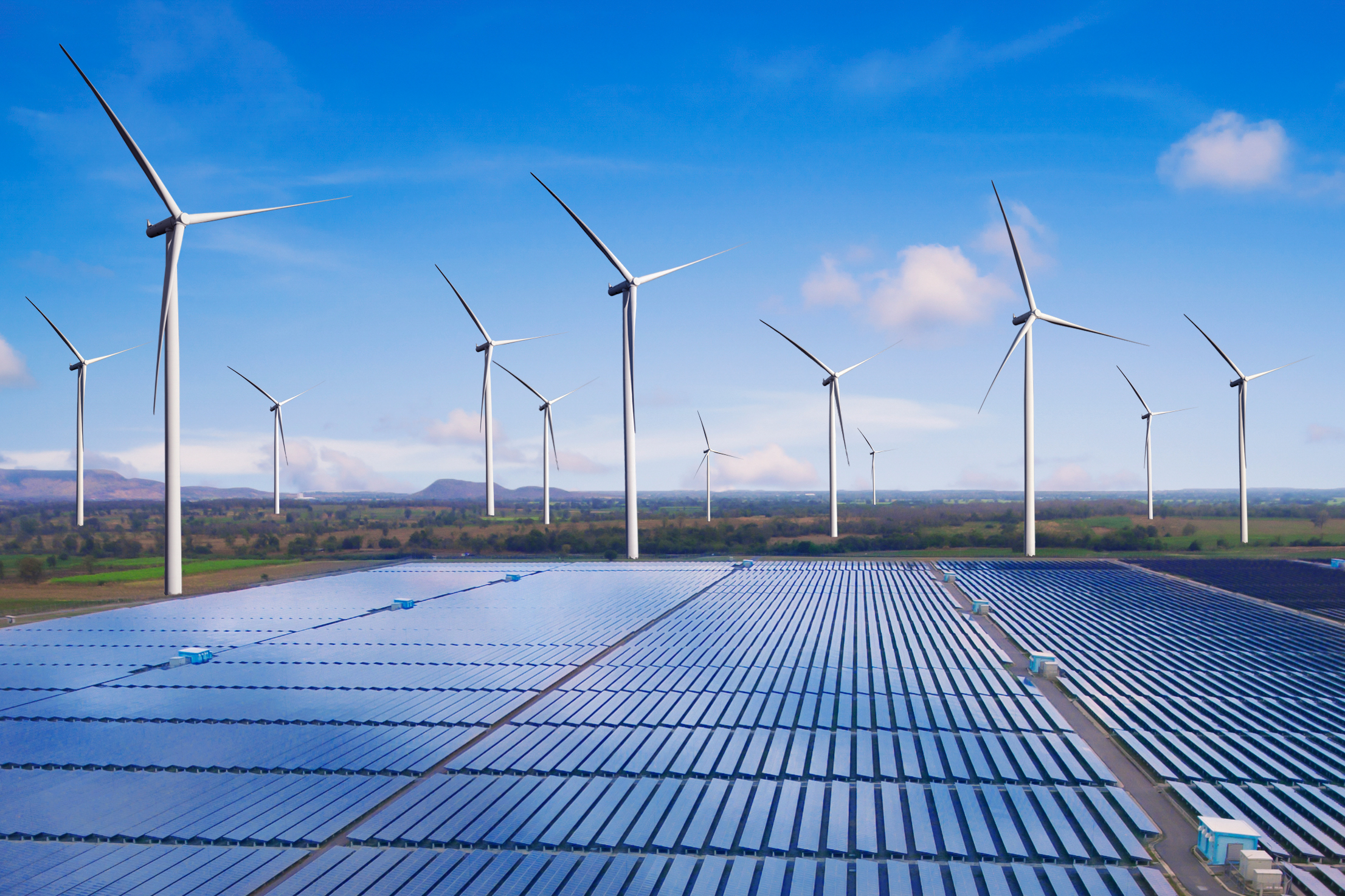 Solar panels and wind turbines in natural landscape.