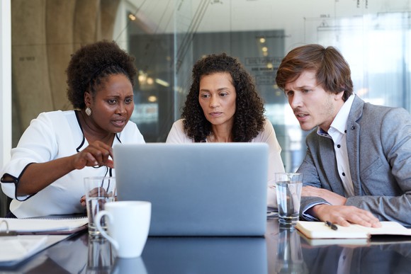 Three life-science professionals looking at stocks on a laptop.