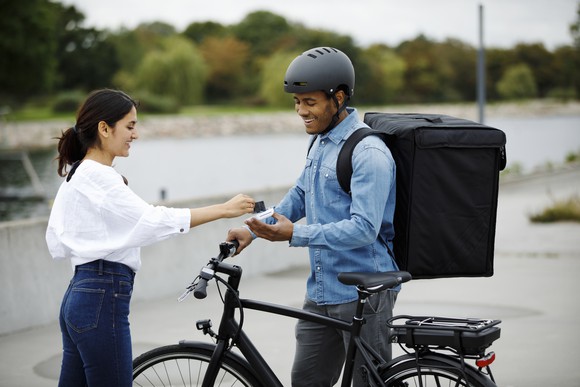 Customer paying delivery person on bike.