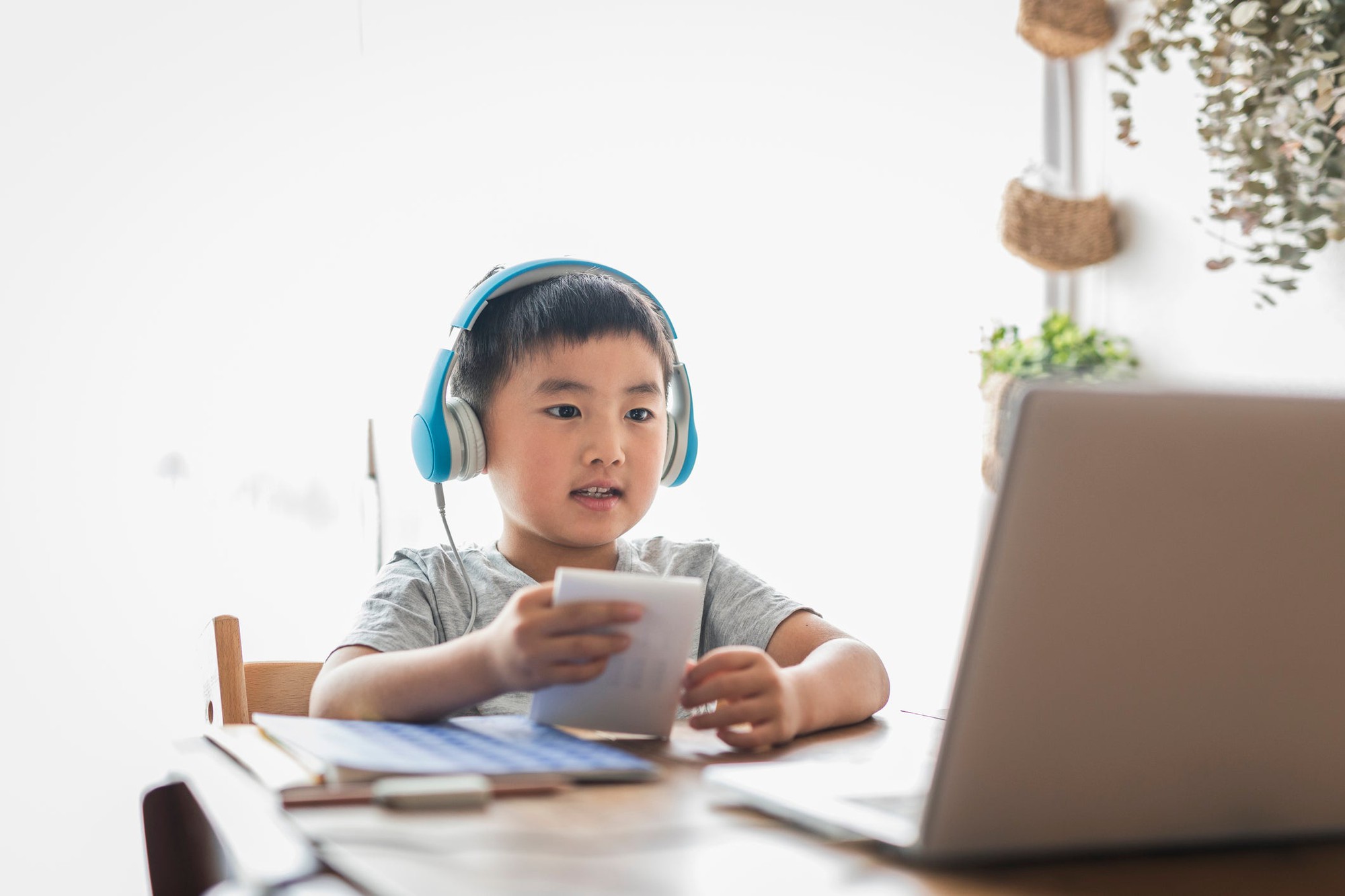 A young child wearing headphones and using a laptop to do schoolwork.