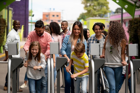 Adults and children moving through turnstiles.