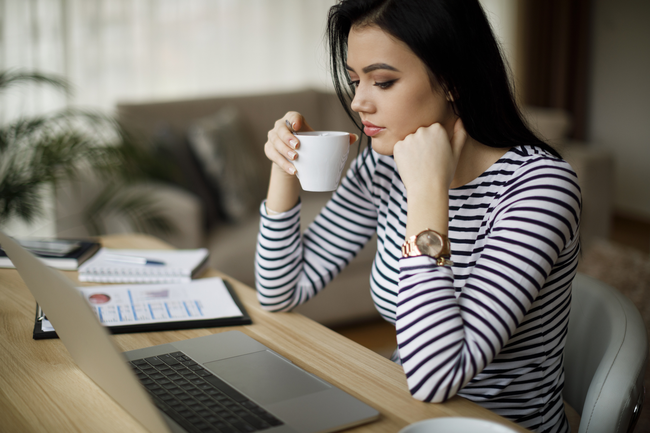 Person sipping coffee while checking their computer.