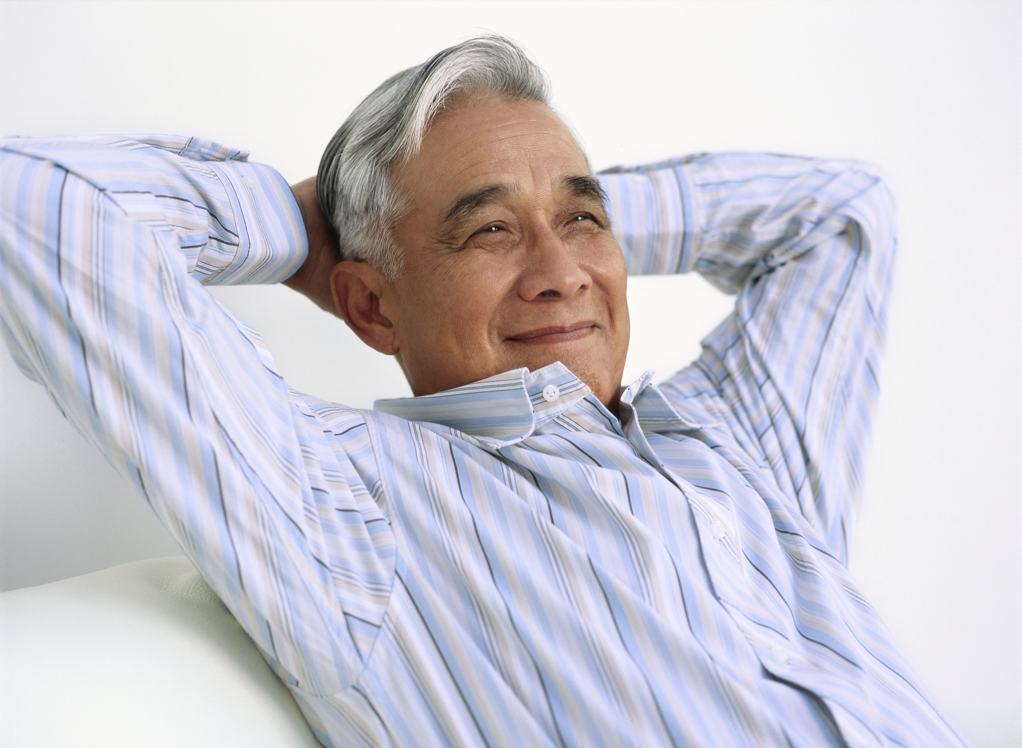 A person smiling with hands held on back of head.
