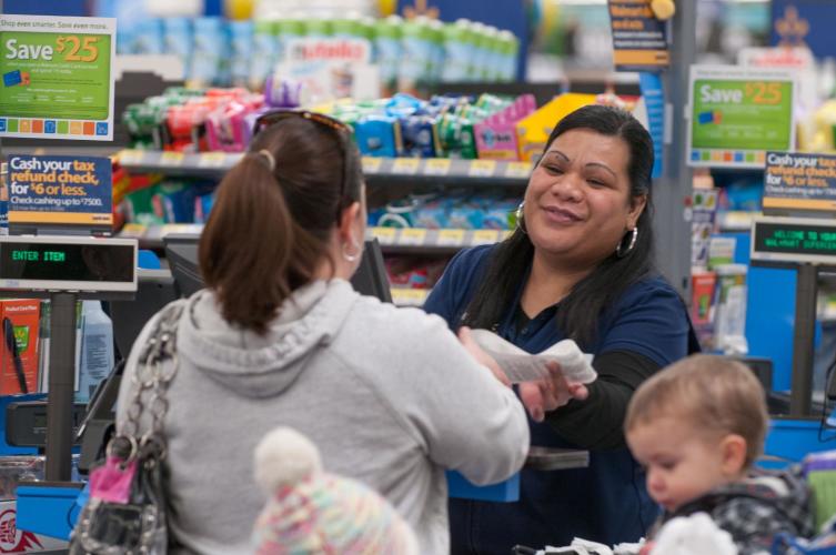 A Walmart cashier handing a receipt to a customer.