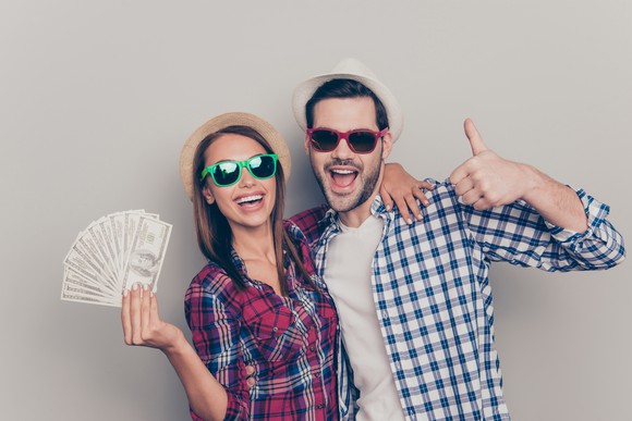 A man and a woman with a fan of cash.