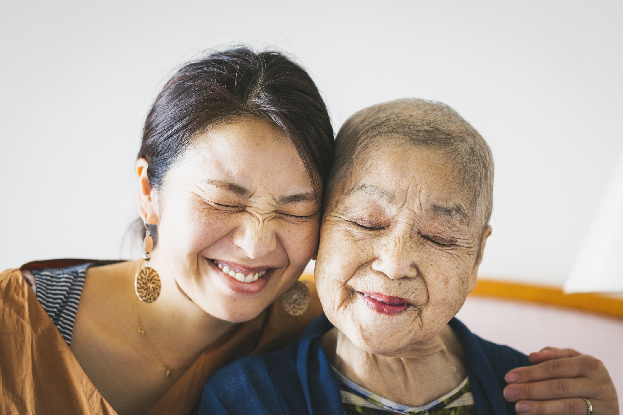 Two adults, one older, are smiling and hugging each other.