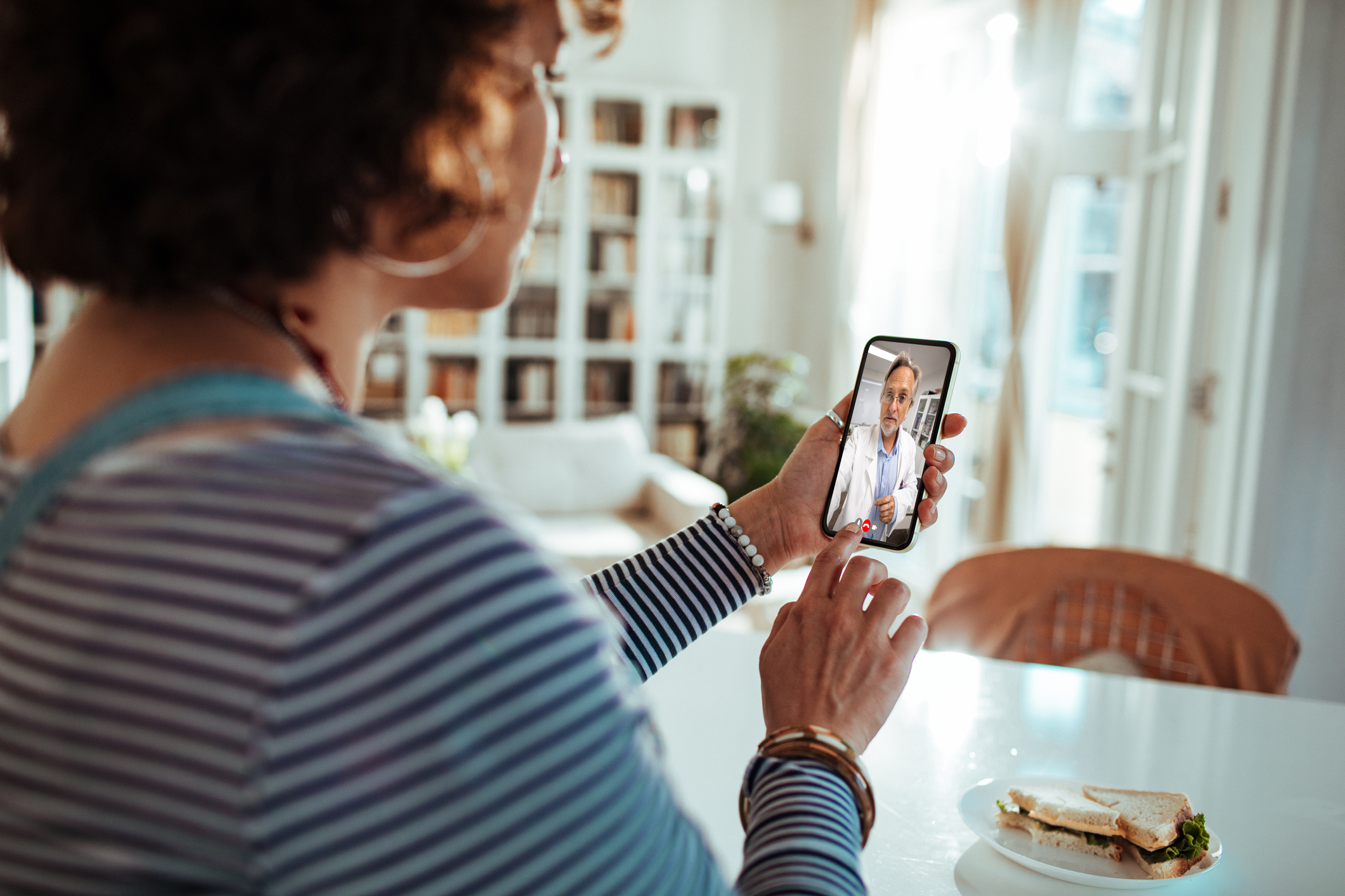 A person using a cell phone to have a meeting with a telemedicine meeting doctor.