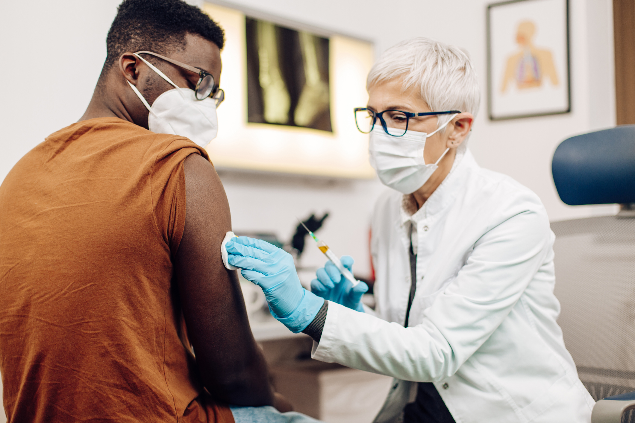 A healthcare professional vaccinates an individual in a medical office.