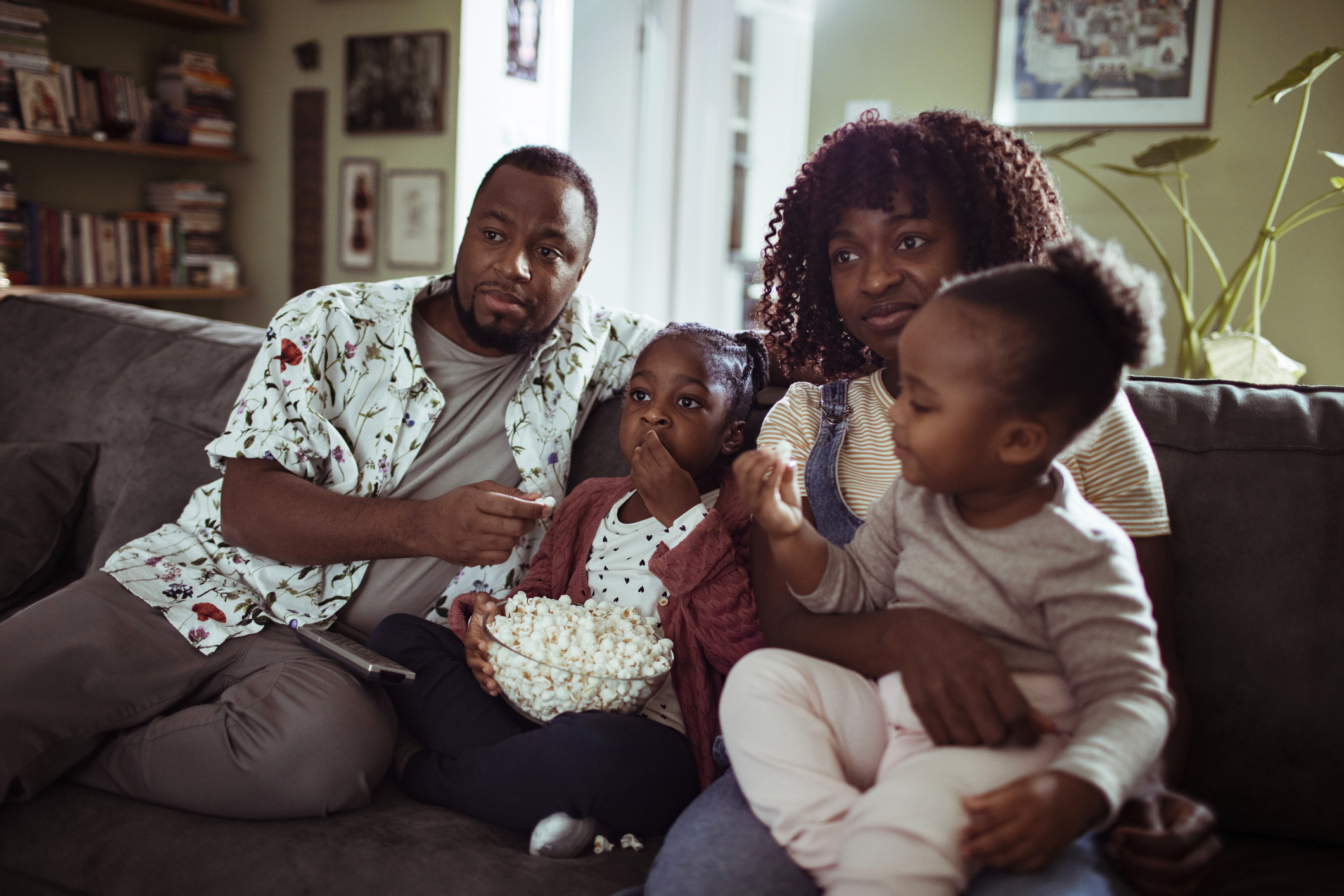 Family sitting on couch with popcorn.