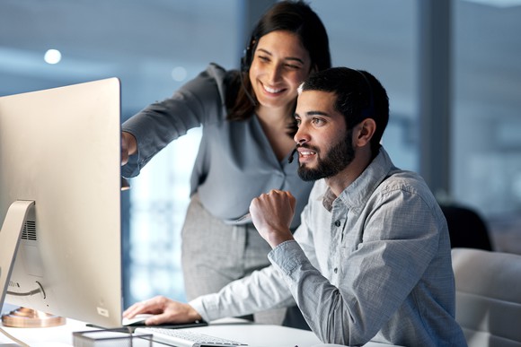 Two people looking at a computer and smiling