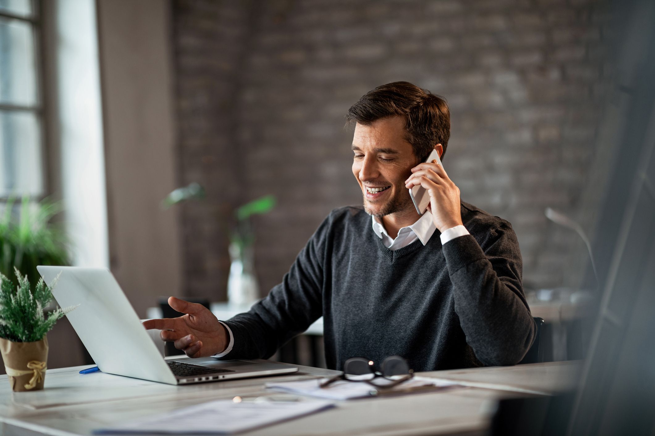 Office worker on smartphone and laptop.