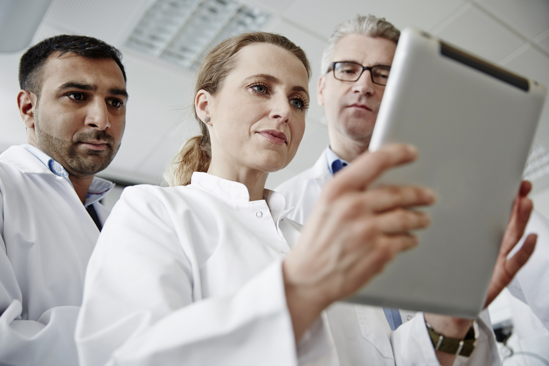 Three doctors looking at a tablet.