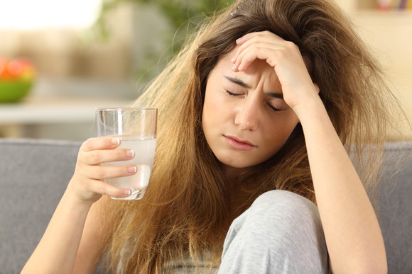 Woman with hangover holding glass