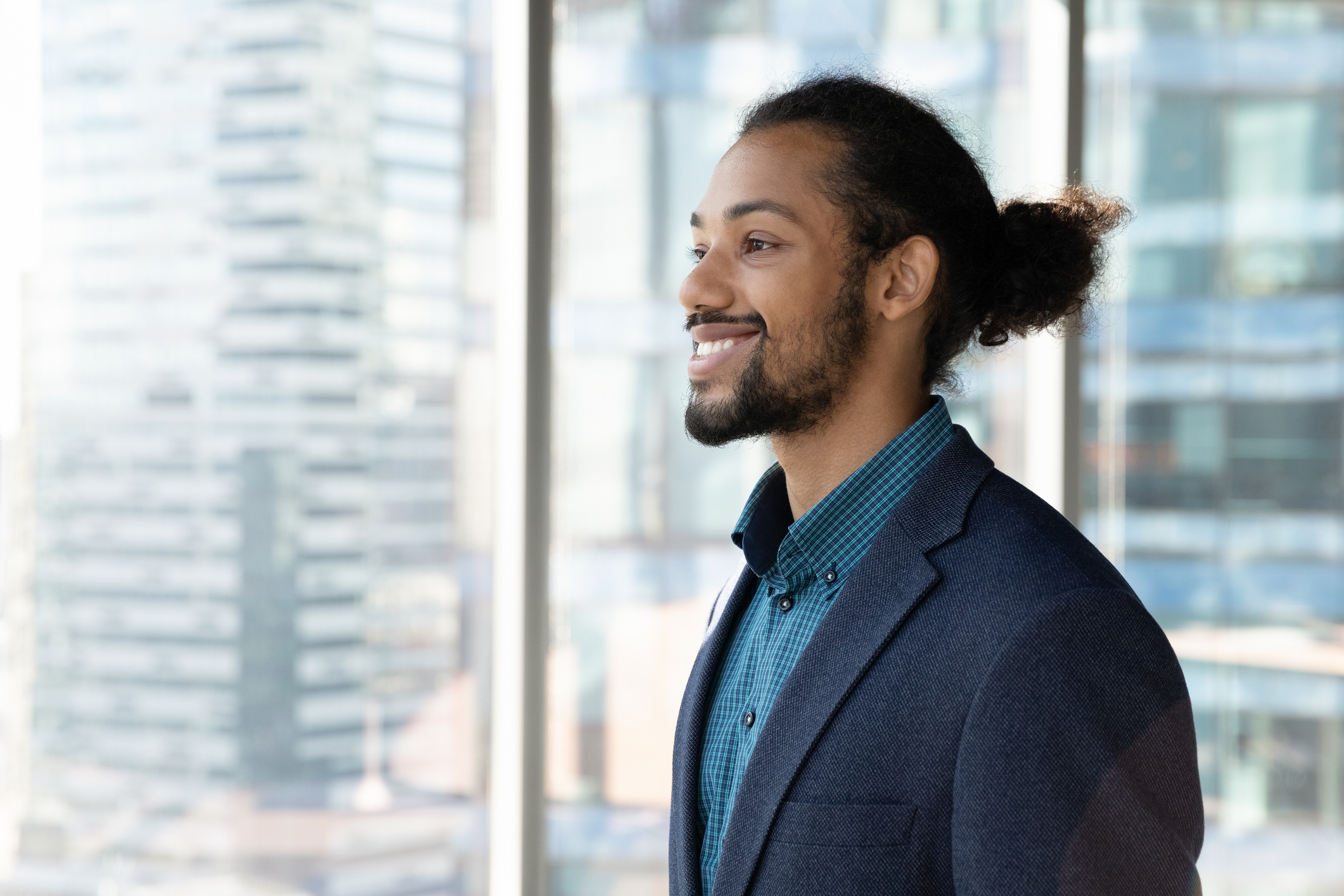 Smiling person looking out office window.