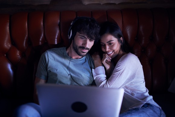 Couple on a couch watching a laptop PC.