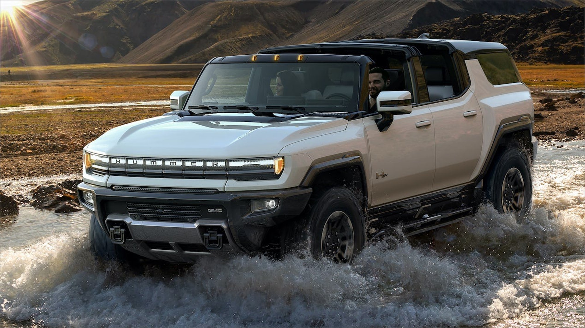 A GMC Hummer EV driving through a shallow pool of water.