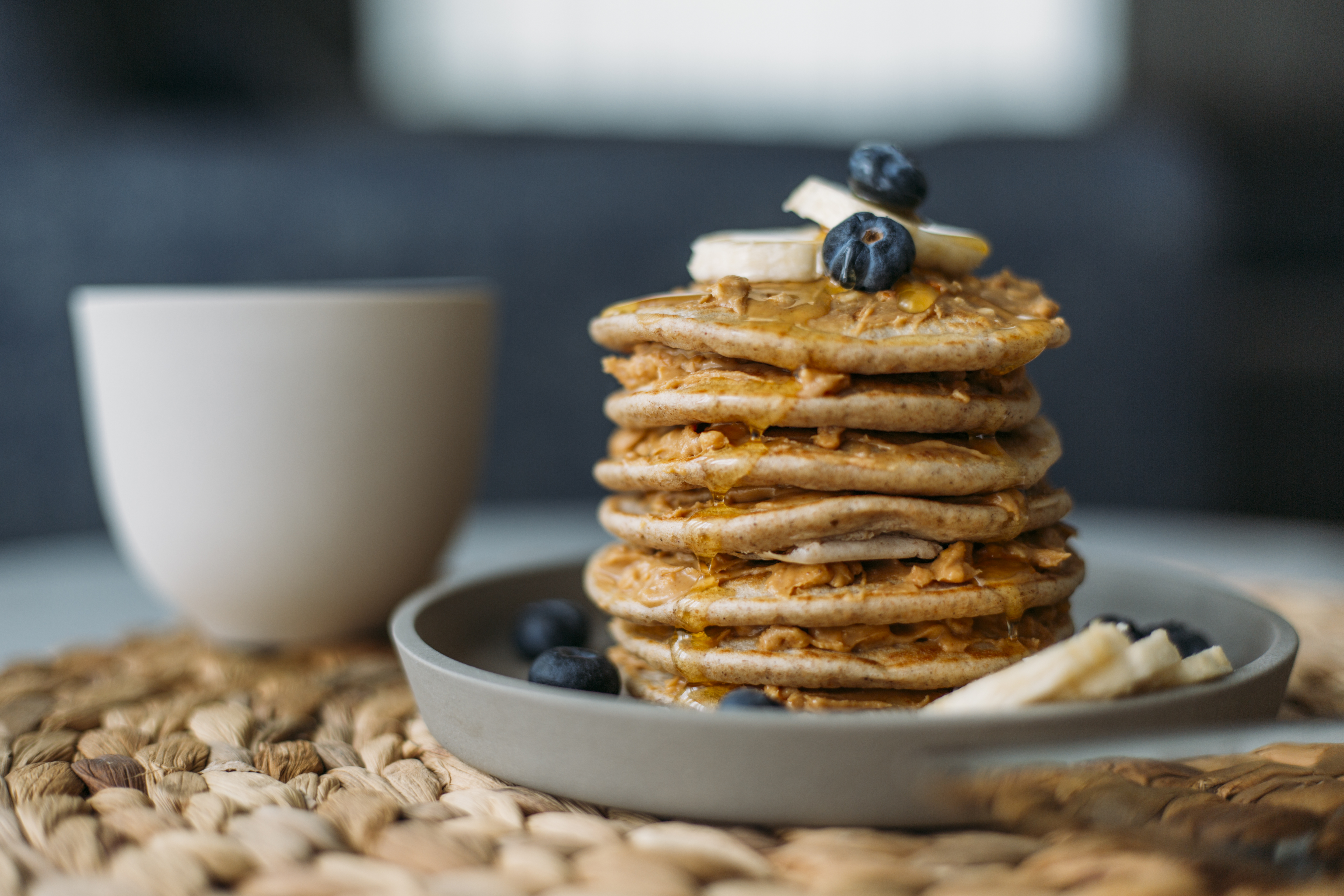Breakfast morning pancakes garnished with blueberries, sliced bananas, and syrup.