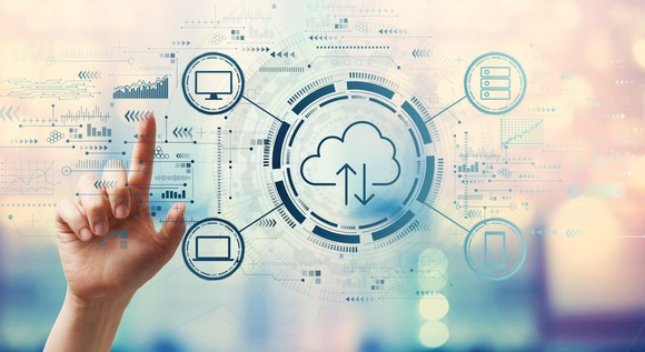 Person pointing in the air to a diagram displaying the cloud connecting to a television, laptop, database, and mobile device