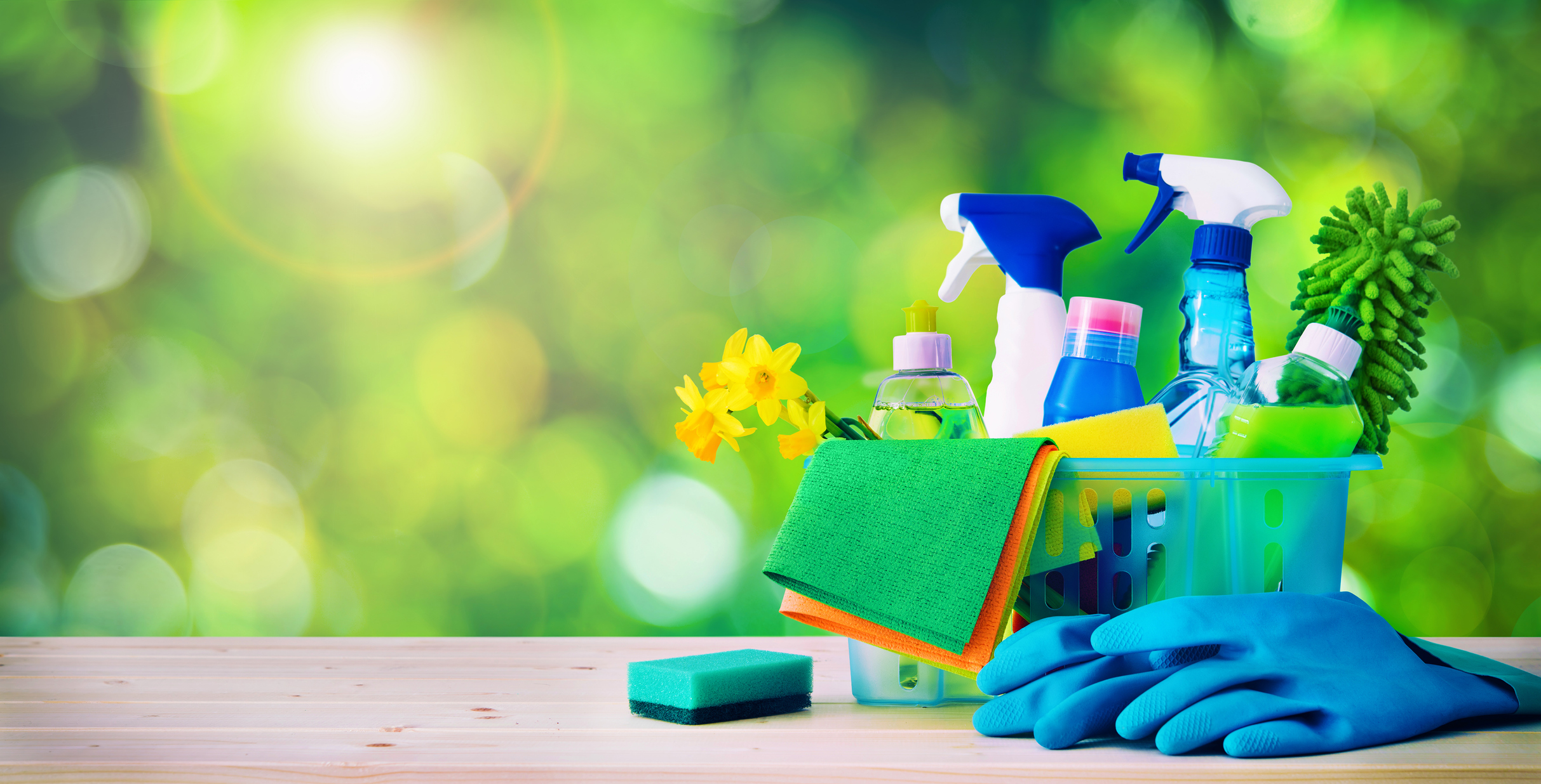 Several cleaning products in a bucket on a table.